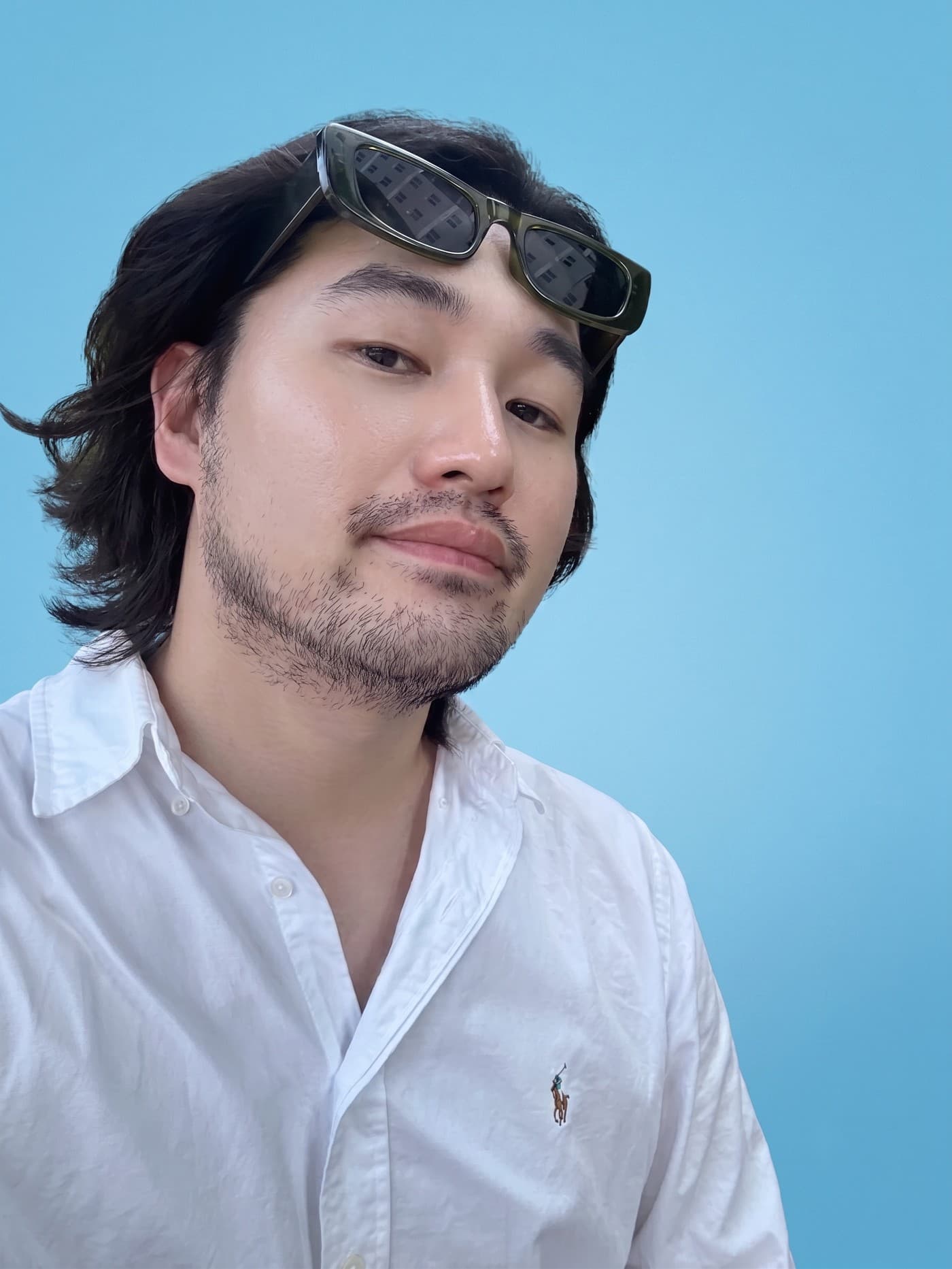 Eddie Jung, sunglasses pushed up, against a blue backdrop